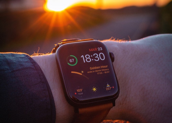 Man wearing Apple Watch at sunset.