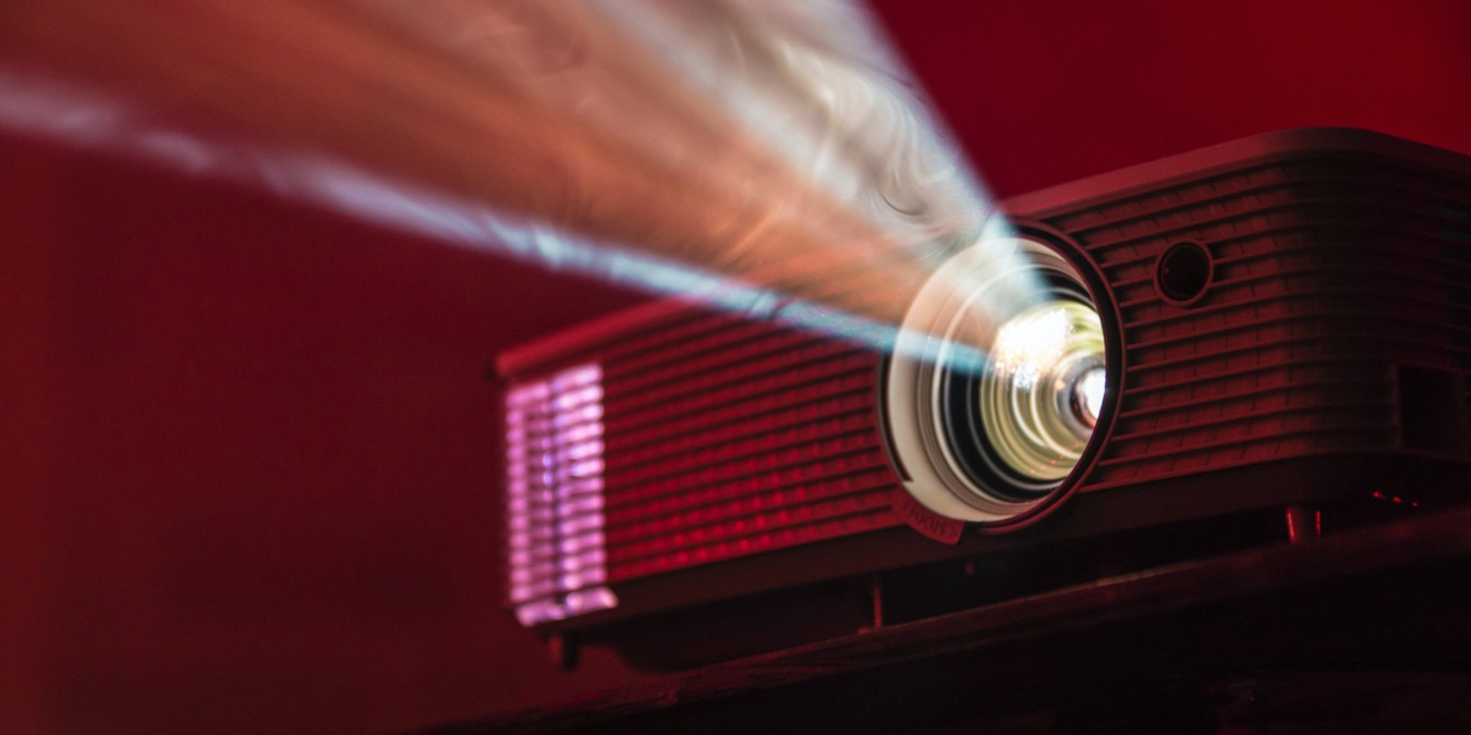 A photograph of a projector running in front of a red background.
