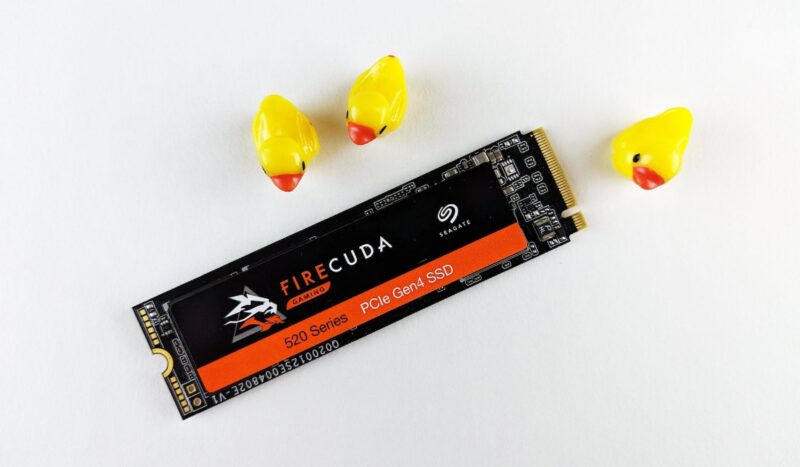 Close up of a Seagate SSD next to some toy ducks on a white background