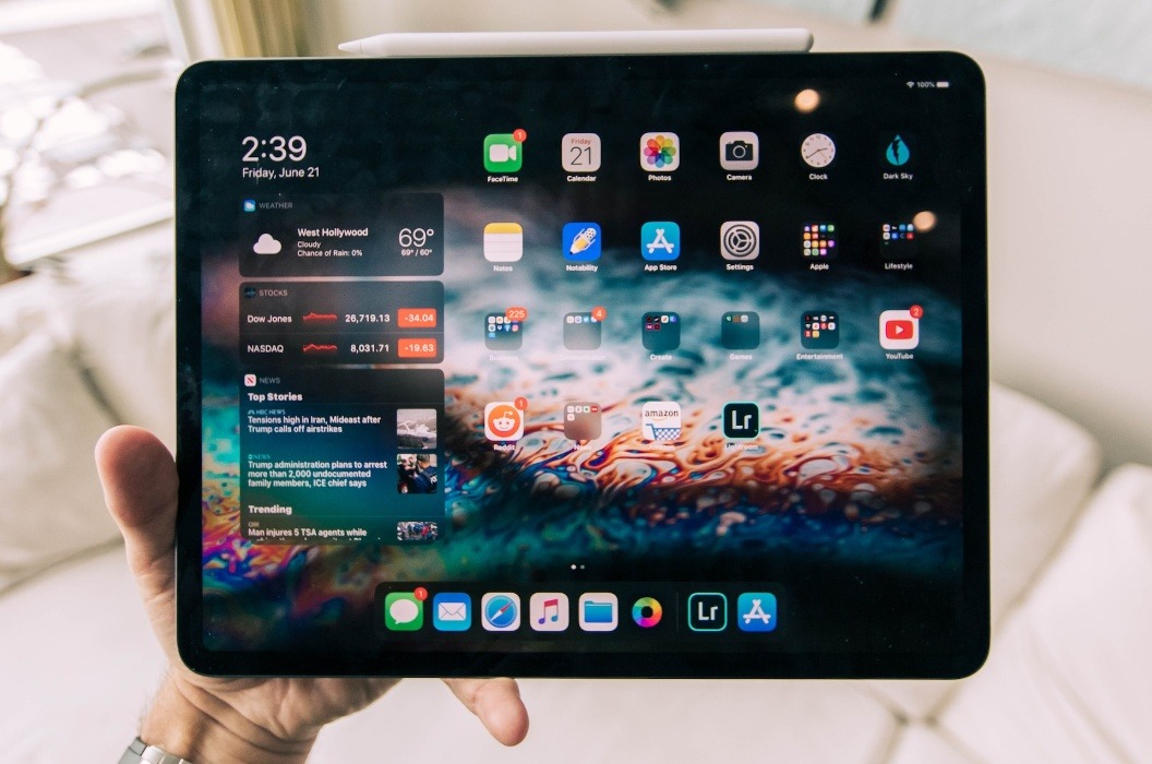 Black iPad Air in a hand against a blurred indoor background