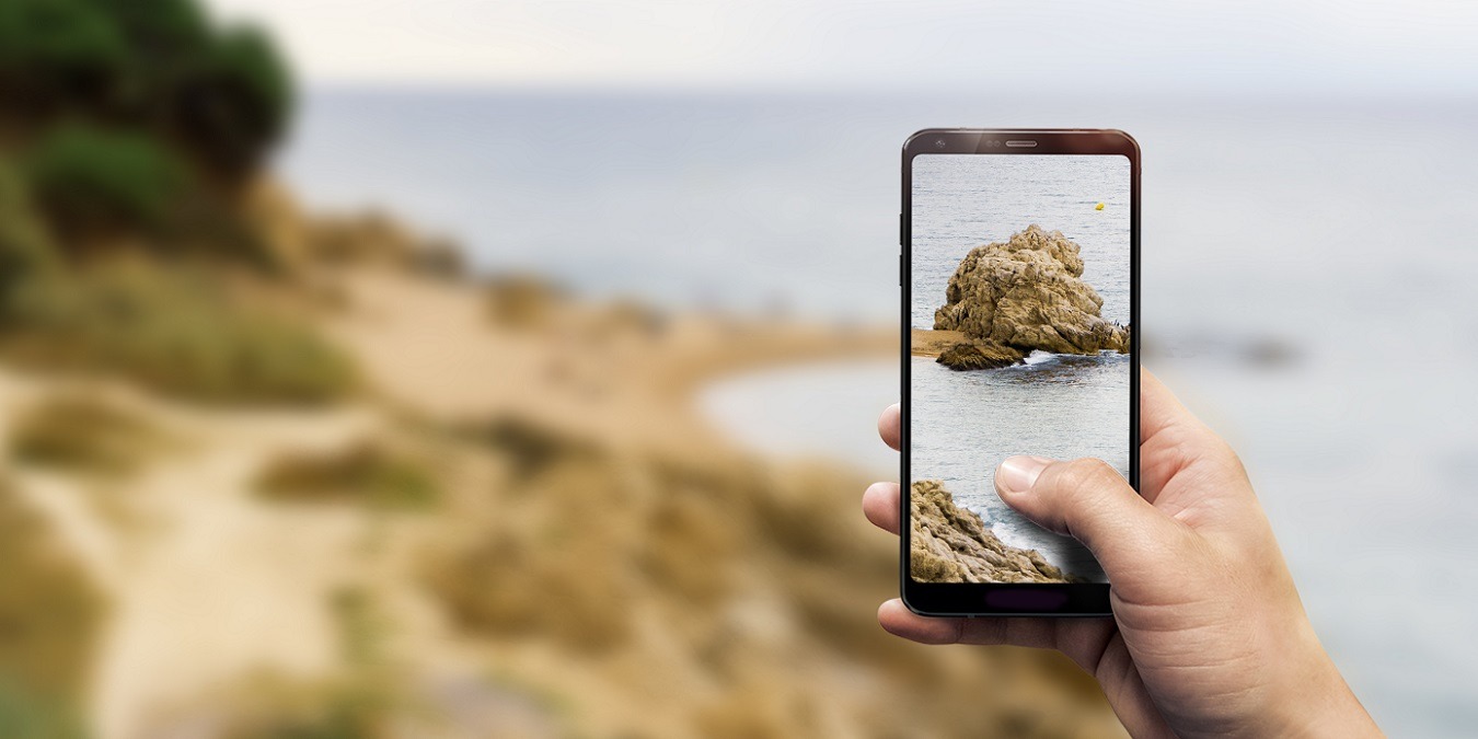 Closeup Of A Hand Holding A Phone Taking A Photo Of A Beach